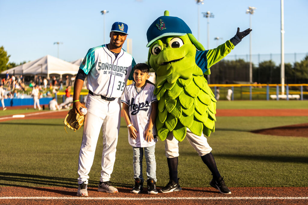 Hillsboro Baseball Player, Young Fan and Mascot pose for camera.